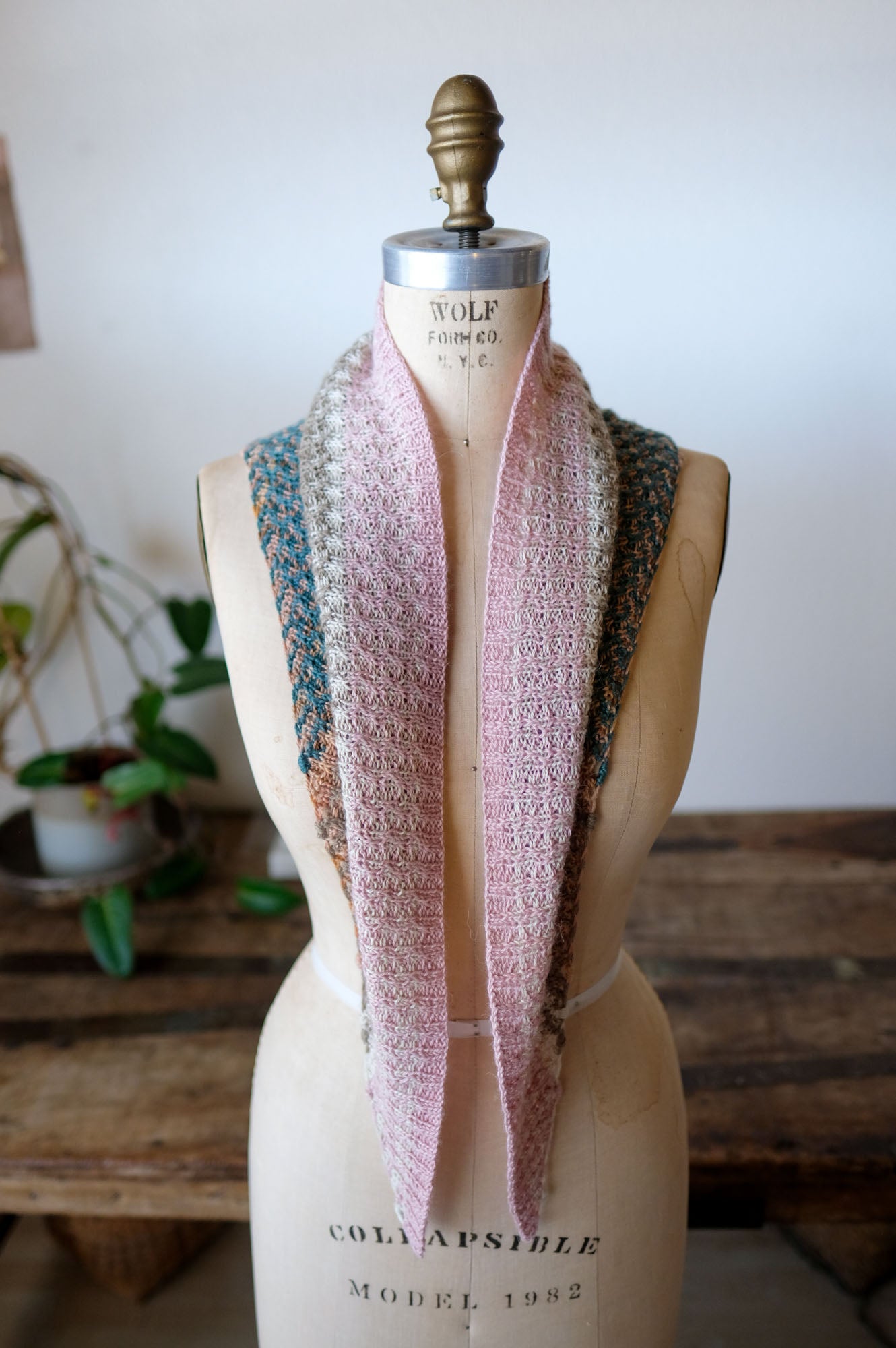 Mannequin wearing a knitted scarf with a blurred indoor background