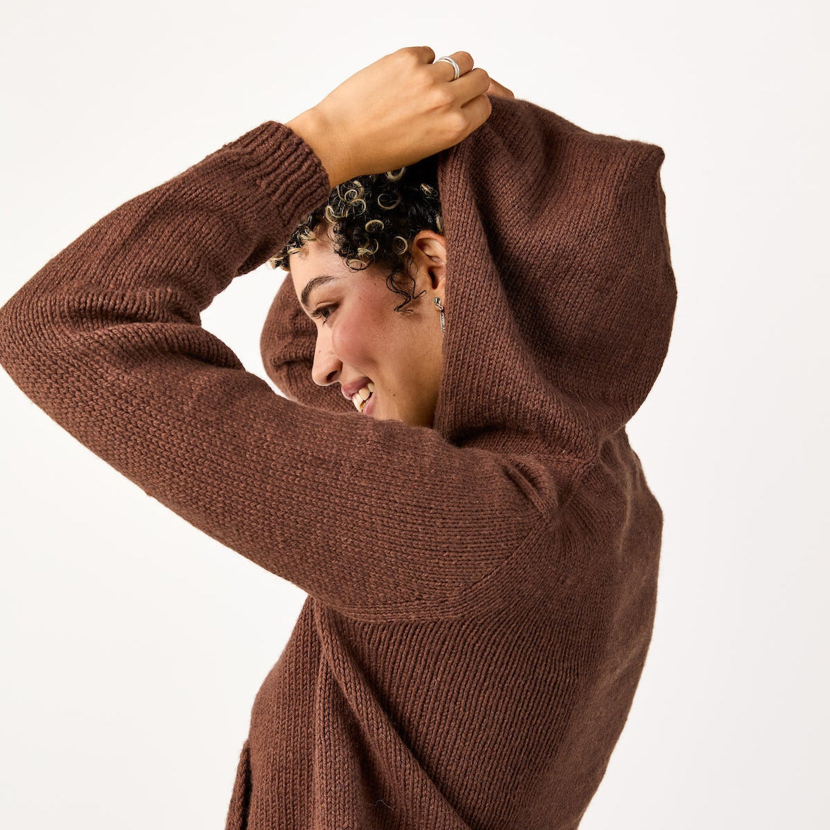 Person wearing a brown sweater with a hood on a white background