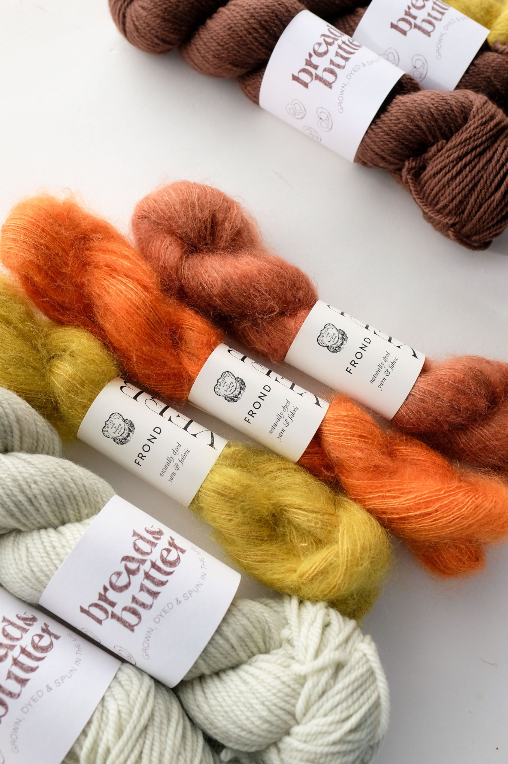 Bread & Butter Yarn skeins shown with AVFKW Frond yarn in various colors on a white background