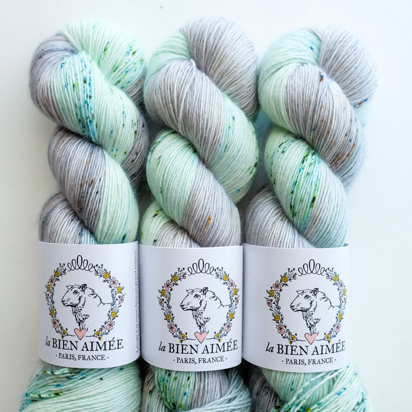 Three skeins of yarn with a visible brand label on a white background