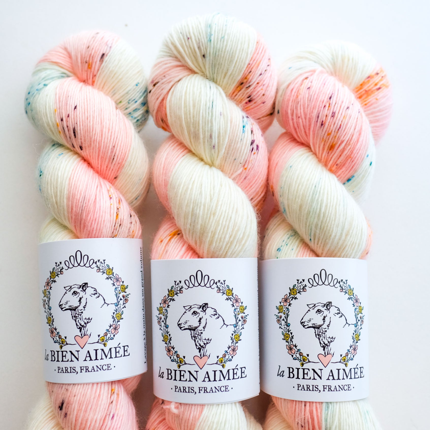 Three skeins of pink and white yarn with visible speckles, labeled 'la BIEN AIMEE PARIS, FRANCE'.