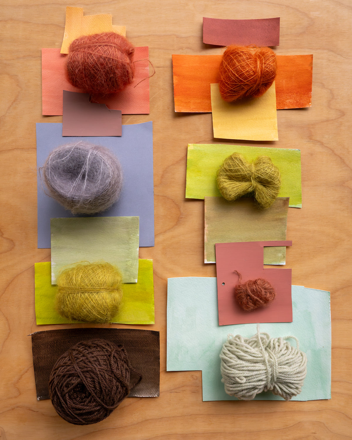 Artistic color theory illustrated with yarn balls on color swatches arranged on a wooden surface