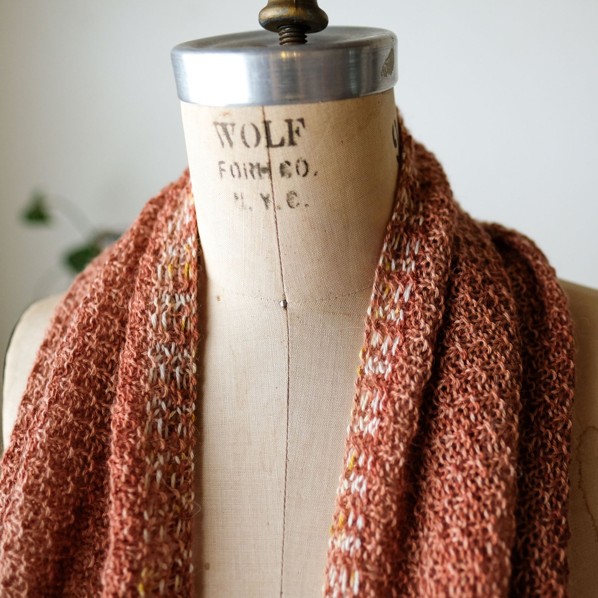 Brown knitted scarf on a mannequin with 'Wolf & Company' label against a neutral background