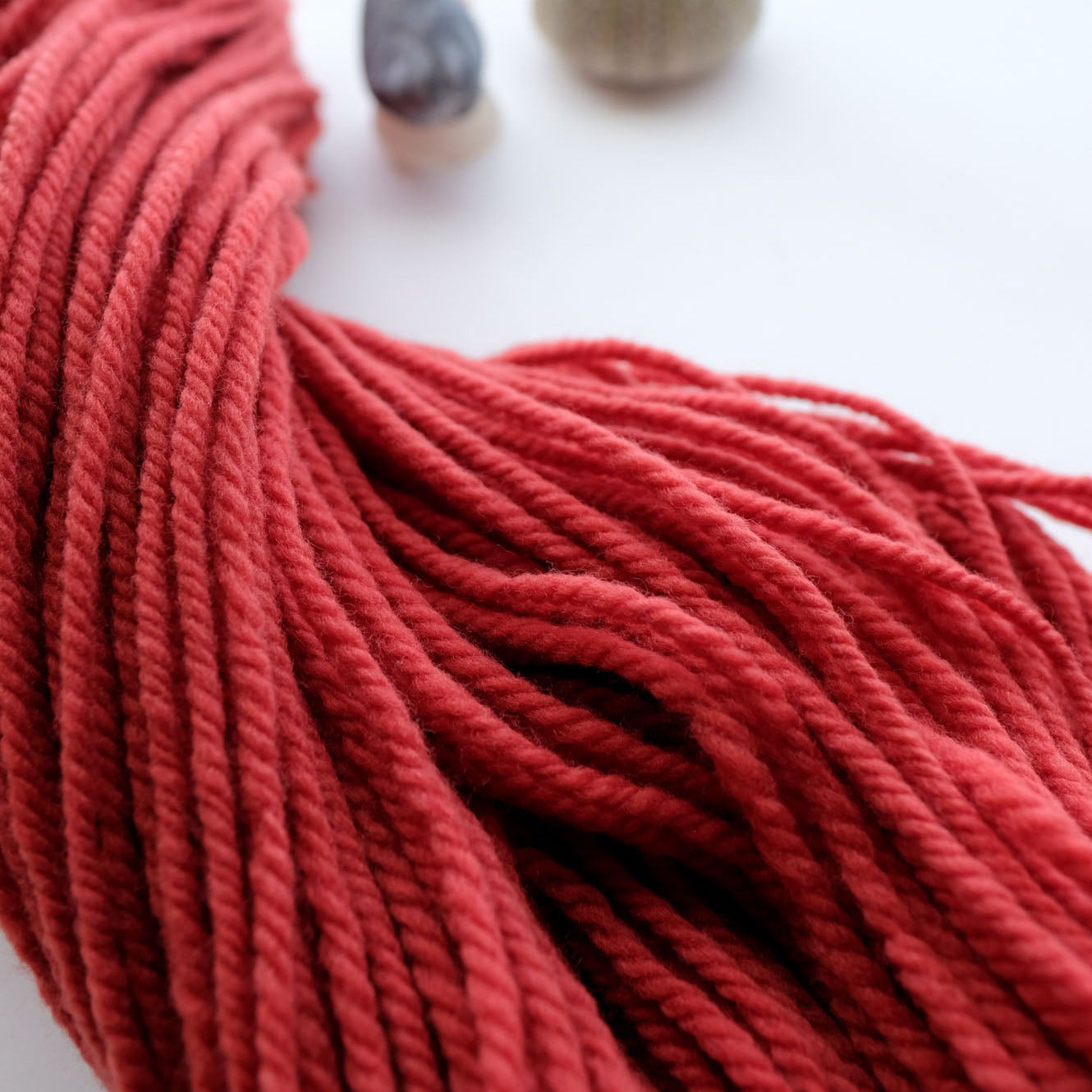 Red yarn with two small stones on a white background