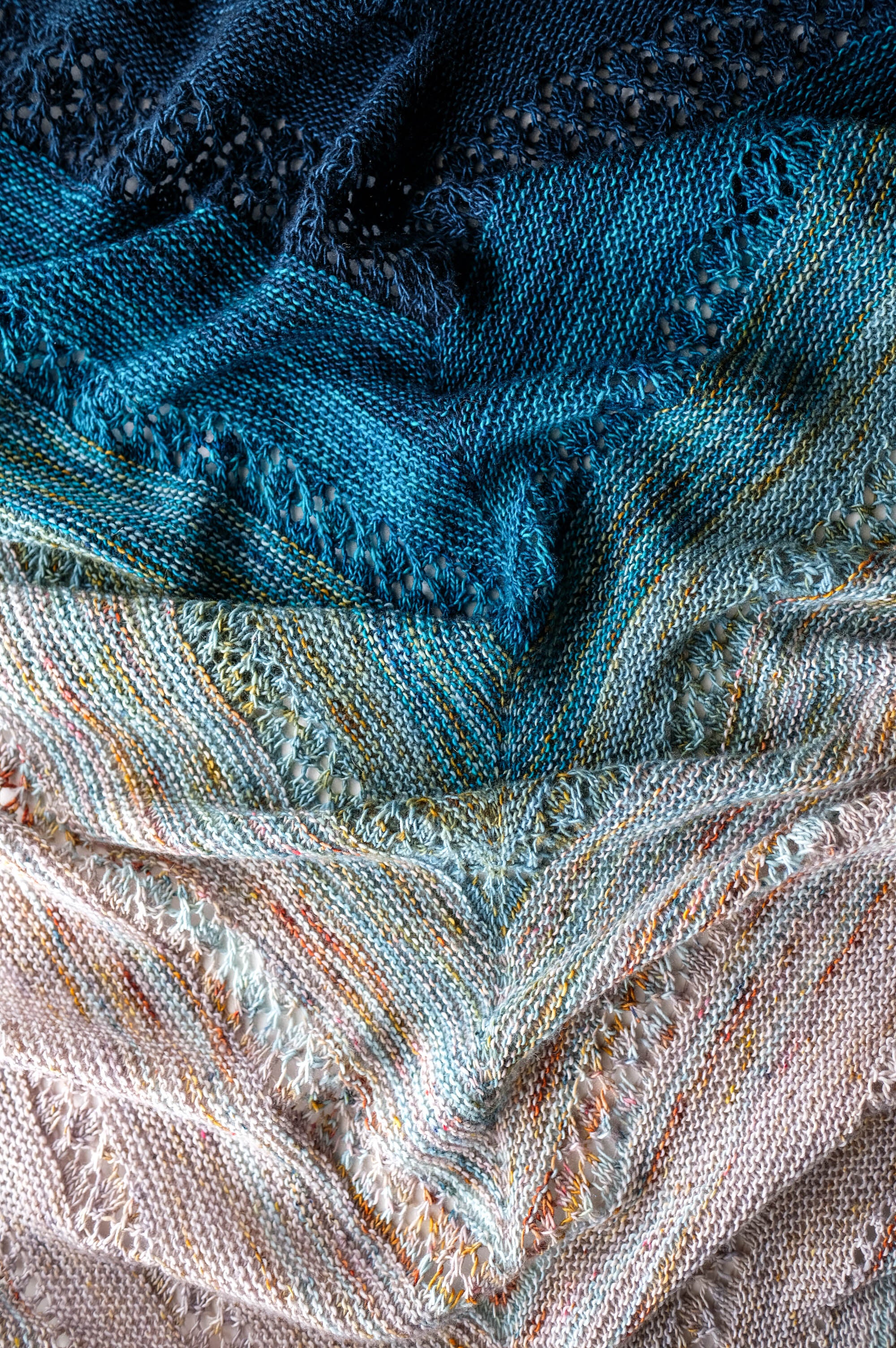 Close-up of a knit fabric hand-knit shawl with blue and multicolor patterns