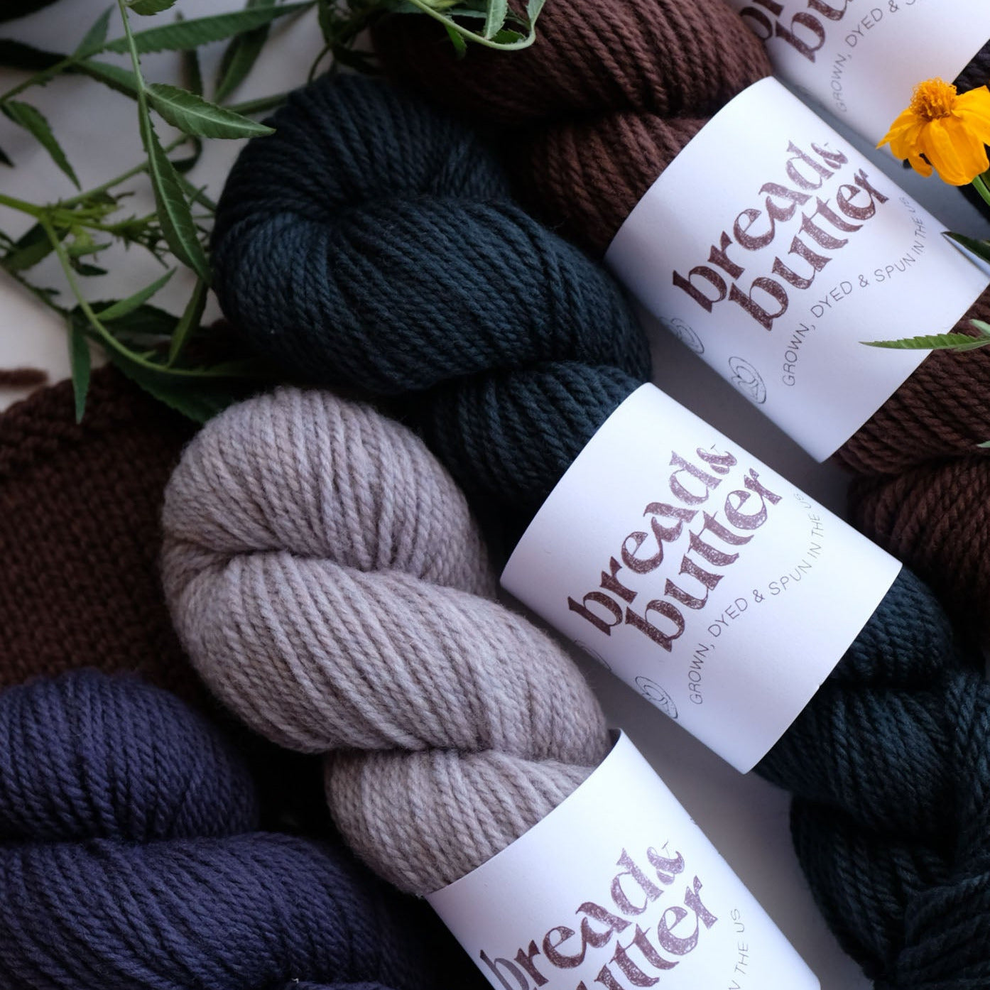 Collection of yarn skeins with 'bread & butter' labels on a rustic background.
