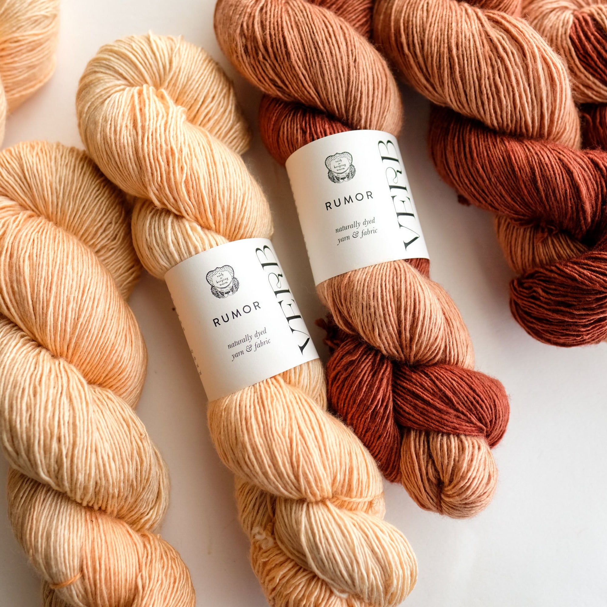 Three skeins of yarn in beige, brown, and red with labels on a white background