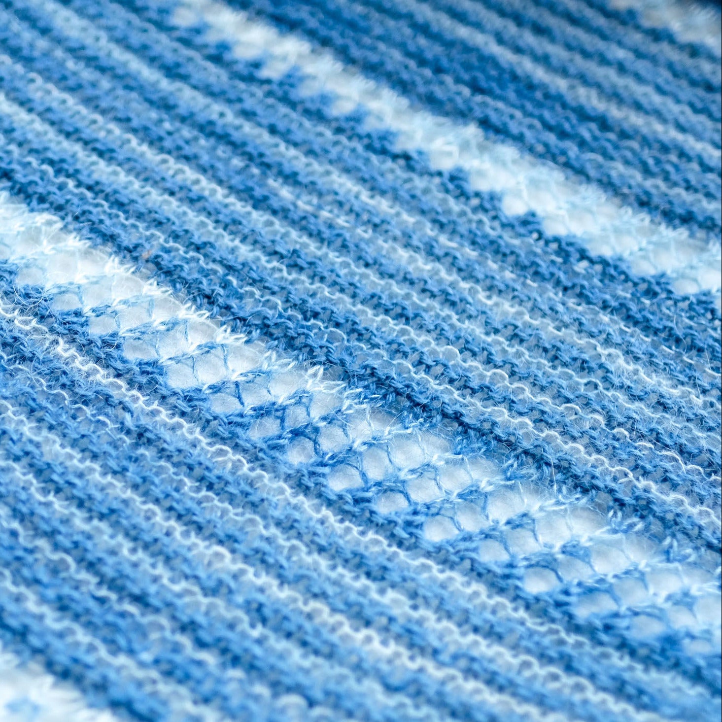 Close-up of natural indigo-dyed yarn with a striped pattern in a hand-knitted shawl.