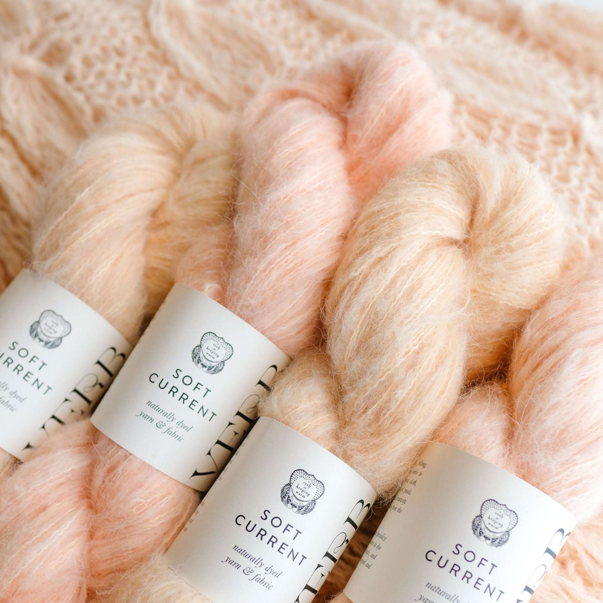 Three skeins of soft pink yarn with 'Soft Current' labels on a textured background.